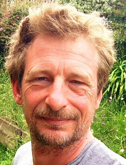 Portrait de Benjamin, magnétiseur au Pays Basque et dans les Landes, souriant en extérieur devant un jardin verdoyant.